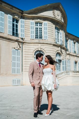 Le couple pose avec élégance devant l'architecture historique majestueuse de l'Hôtel de Ville de Marseille.