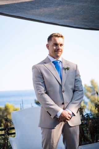 Portrait du marié ému attendant sa future femme devant l'arche nuptiale sur la Côte d'Azur.