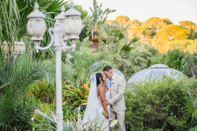 Portrait romantique des mariés s'enlaçant dans la végétation luxuriante du lieu de réception de Toulon.