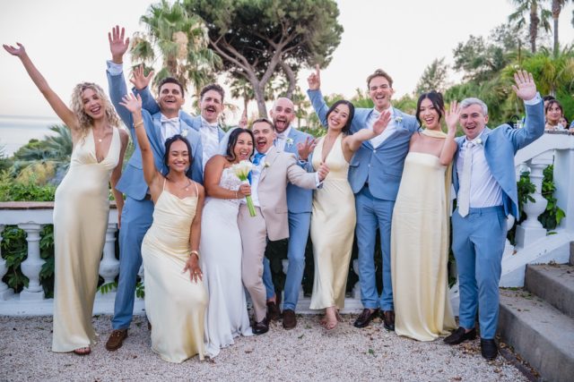Photo de groupe fun et décalée avec les demoiselles et garçons d'honneur levant les bras.