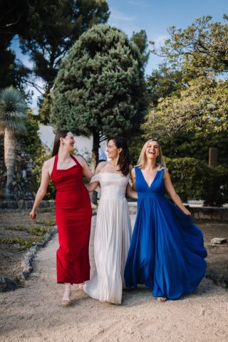La mariée marche en éclatant de rire avec ses demoiselles d'honneur dans les jardins luxuriants du domaine toulonnais.