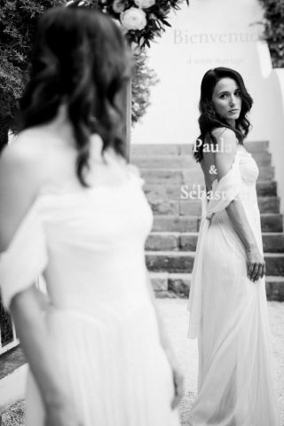 Élégant portrait en noir et blanc de la mariée se retournant sur les marches en pierre du domaine dans le Var.
