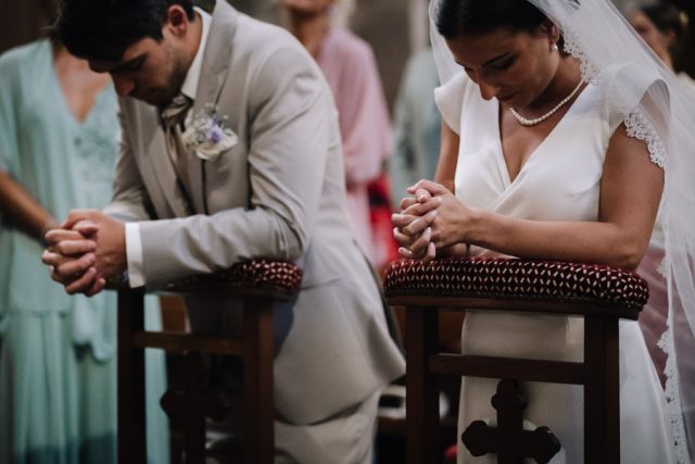 Les mariés assis de dos écoutent les lectures lors de leur messe de mariage à Fréjus.