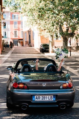 Les mariés quittent l'église à bord d'une voiture cabriolet de collection sur la Côte d'Azur.