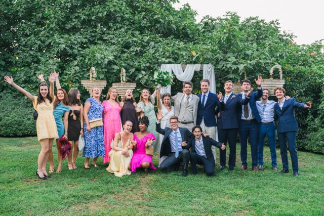 Photo de groupe festive avec tous les témoins et demoiselles d'honneur levant les bras.