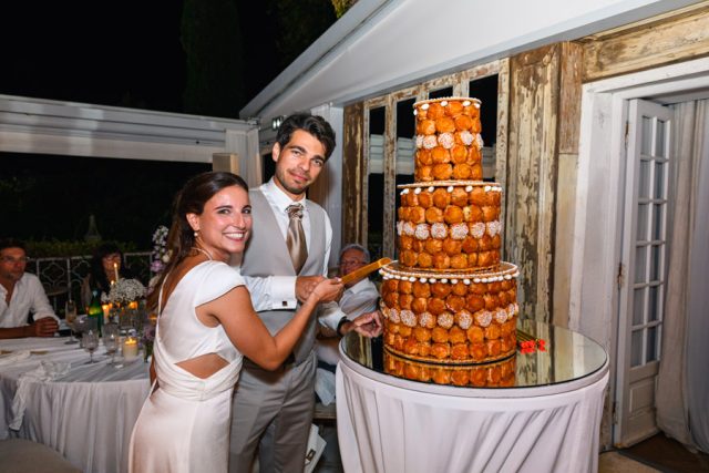 Les mariés posent fièrement devant leur gâteau de mariage traditionnel français.
