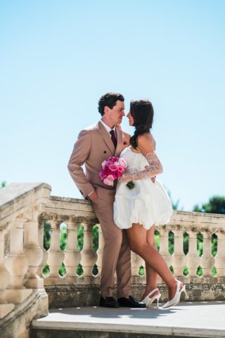 Les mariés accoudés à une balustrade en pierre profitent d'un instant de calme lors de leur séance couple.
