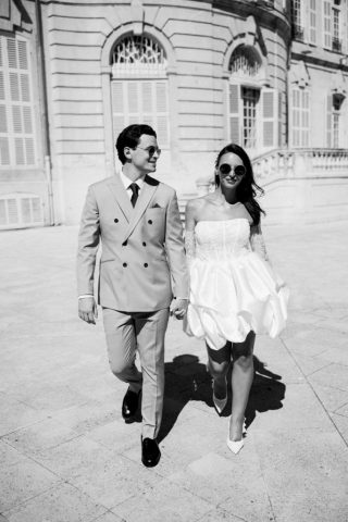 Portrait en noir et blanc très graphique du couple marchant vers l'objectif avec leurs lunettes de soleil.