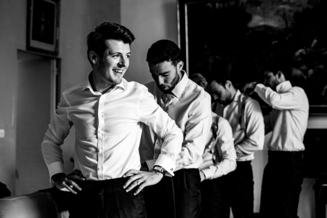 Le marié et ses témoins s'habillent dans la bonne humeur, photographie en noir et blanc.