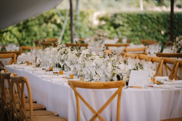 Élégante décoration florale blanche et verte sur les tables en bois du dîner de mariage.