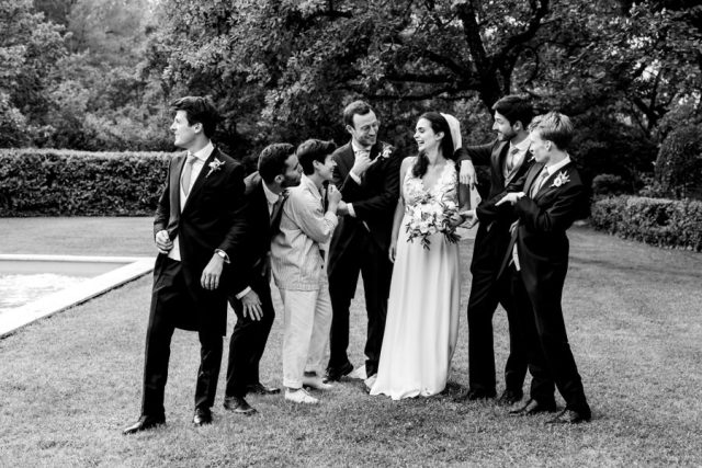 Le marié et ses témoins rigolent dans les jardins du domaine, photo en noir et blanc.