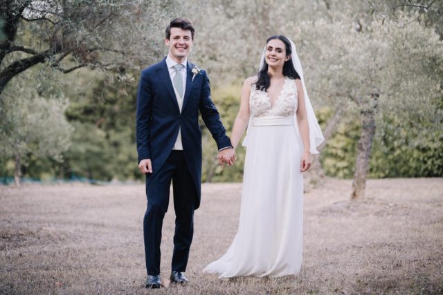 Les jeunes mariés se promènent main dans la main au milieu des oliviers provençaux.