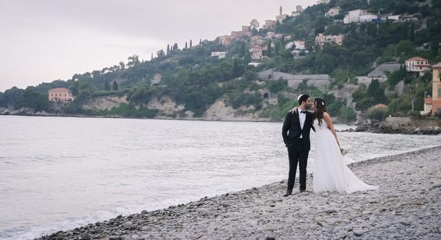 Baiser romantique du couple sur la plage avec la mer et la côte italienne en arrière-plan.