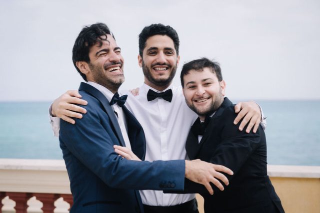 Le marié sourit, entouré de ses témoins en chemise blanche sur la terrasse en Italie.