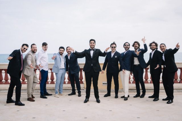 Photo de groupe dynamique du marié et de ses garçons d'honneur sur la terrasse vue mer.