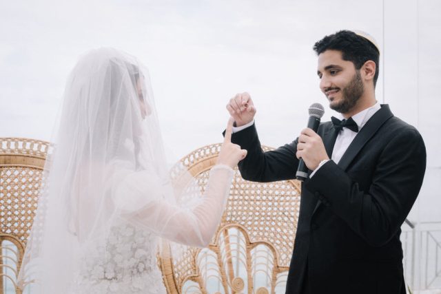 Le marié passe l'anneau au doigt de la mariée sous la Houppa lors de l'union religieuse.