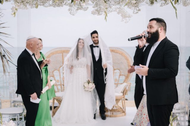 L'officiant prononce les bénédictions sous la Houppa face au couple et à la Méditerranée.