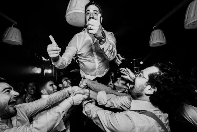 Le marié est jeté en l'air par ses amis lors de la soirée (Photographie en noir et blanc).