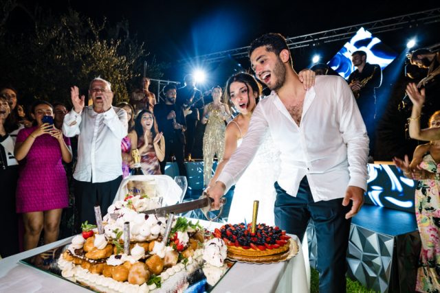 Le couple découpe le gâteau de mariage, une immense tarte aux fruits italienne, pendant la soirée.