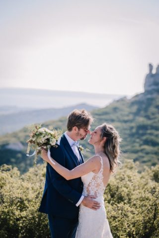 Le marié embrasse tendrement sa femme lors de la séance photo au milieu de la nature.