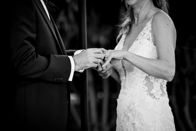 Gros plan sur l'échange des alliances lors du mariage civil immortalisé en noir et blanc.