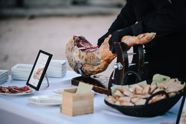 Découpe d'un jambon ibérique sur un stand lors du vin d'honneur de la réception.