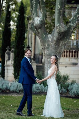 Portrait des mariés posant fièrement devant l'architecture unique du Château de la Beaumetane.