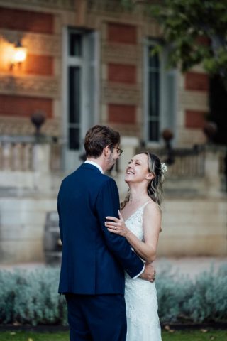 Le marié tient sa femme par la taille, portrait romantique et souriant dans les jardins.