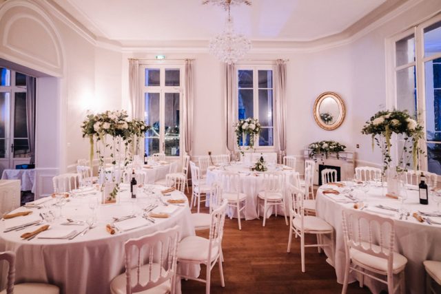Décoration de la salle de réception avec tables rondes et chaises médaillon pour le dîner.