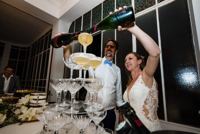 Magali et Yann versent ensemble le champagne sur la grande pyramide de coupes lors de la soirée.