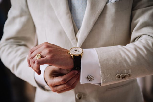 Gros plan sur les mains du marié ajustant sa montre le matin du mariage.