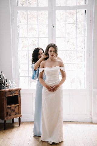 Les proches de la mariée l'aident à boutonner le dos de sa robe au Château de la Beaumetane.