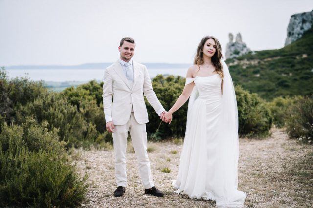 Les mariés marchent souriants vers l'objectif dans un paysage naturel de Provence