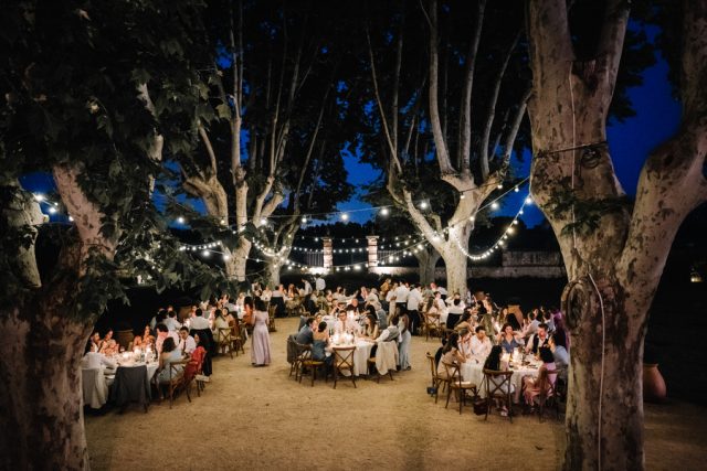 Dîner de mariage féérique en extérieur sous les guirlandes lumineuses style guinguette au château.