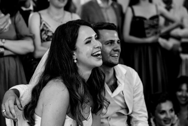 Éclat de rire complice des mariés pendant le repas, capturé en noir et blanc par Gilles Perbal.