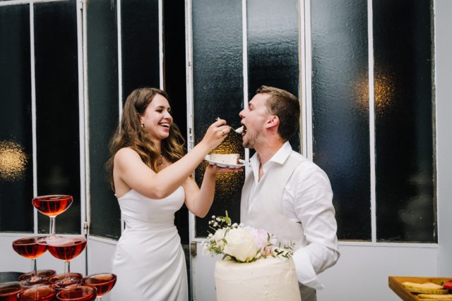 La mariée donne une part de gâteau au marié, moment de complicité festif.