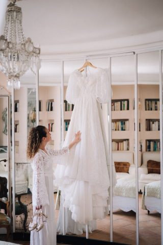 La mariée admire sa superbe robe de mariée suspendue dans sa suite lors des préparatifs au domaine.