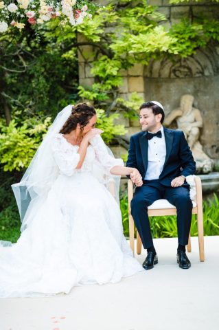 Les mariés rient aux éclats, assis sous l'arche nuptiale pendant la célébration de leur mariage.