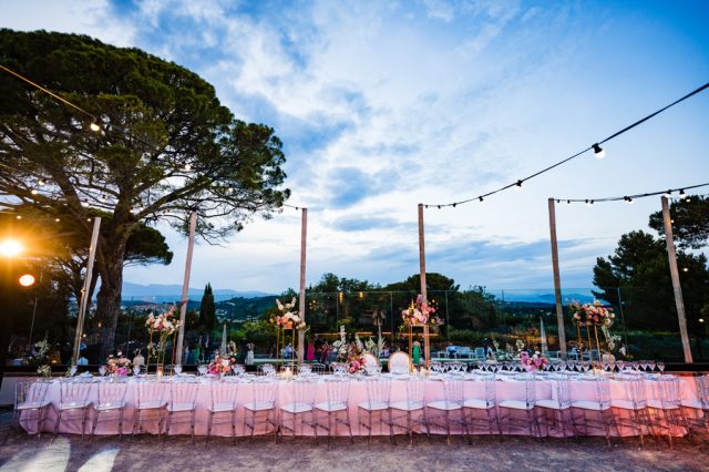 Dîner de mariage exceptionnel en extérieur avec de longues tablées sous les guirlandes lumineuses à Antibes.