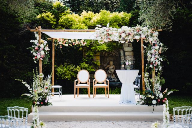 Installation élégante de la Houppa décorée de fleurs blanches pour la cérémonie religieuse dans les jardins.