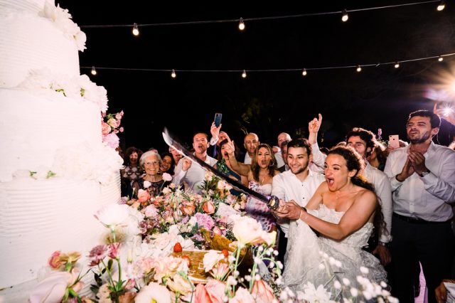 Découpe du magnifique gâteau de mariage fleuri par les jeunes mariés sur la Côte d'Azur.