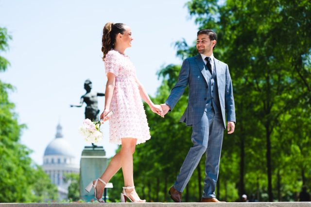 Promenade romantique des mariés main dans la main dans les allées arborées du parc parisien.